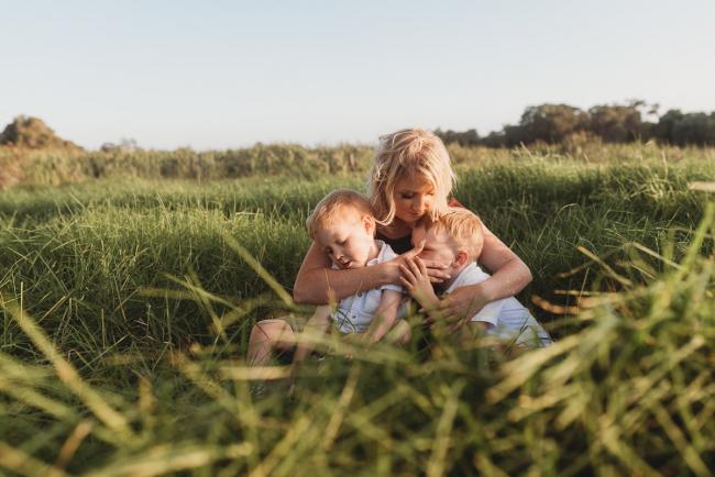 mother in the grass with two sons during golden hour at Perry's Paddock with Perth Family Photographer Alana Prosper Photography