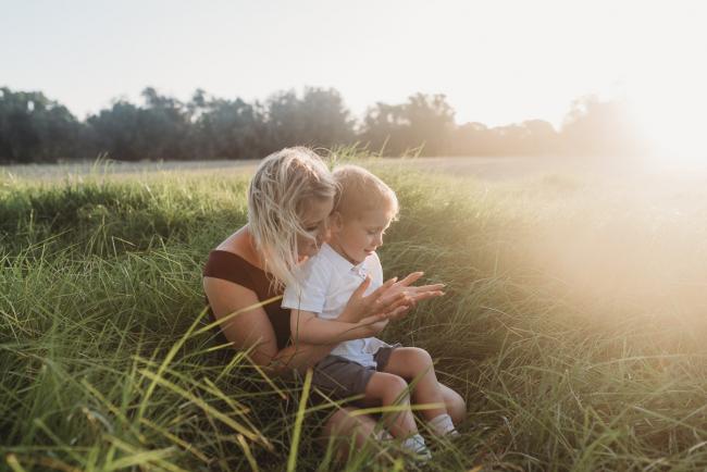 mother sitting in grass with little boy on lap during golden hour at Perry's Paddock with Perth Family Photographer Alana Prosper Photography