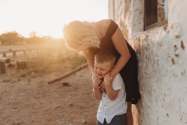 mother bending down with arms around son during golden hour at Perry's Paddock with Perth Family Photographer Alana Prosper Photography
