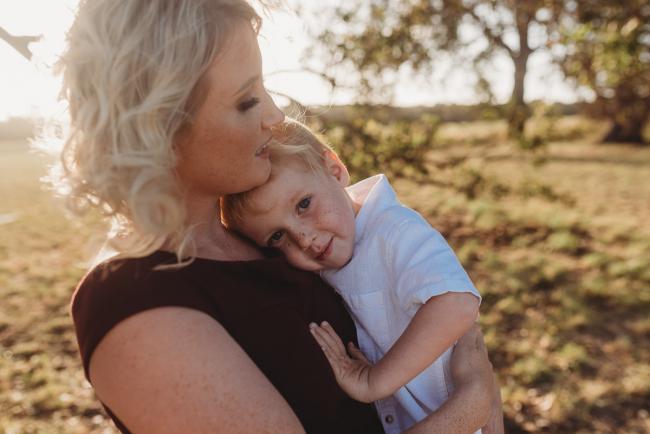 Son cuddling into mother during golden hour at Perry's Paddock with Perth Family Photographer Alana Prosper Photography