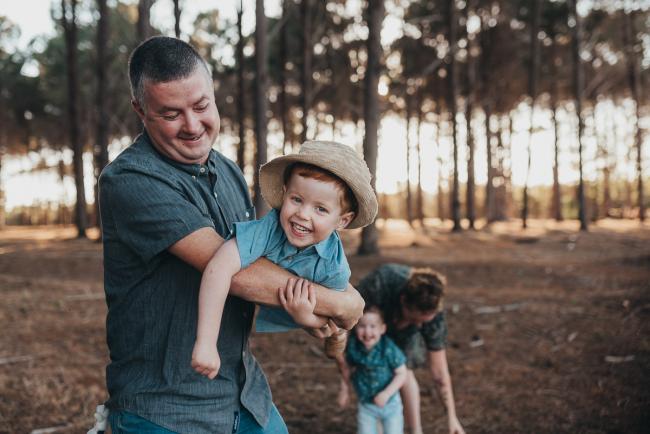 father flying little boy through the air during Perth family photography session at The Pines Perth with Alana Prosper Photography