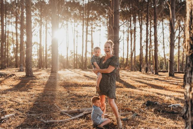 Mother holding one son while the other son hugs her legs during Perth family photography session at The Pines Wanneroo
