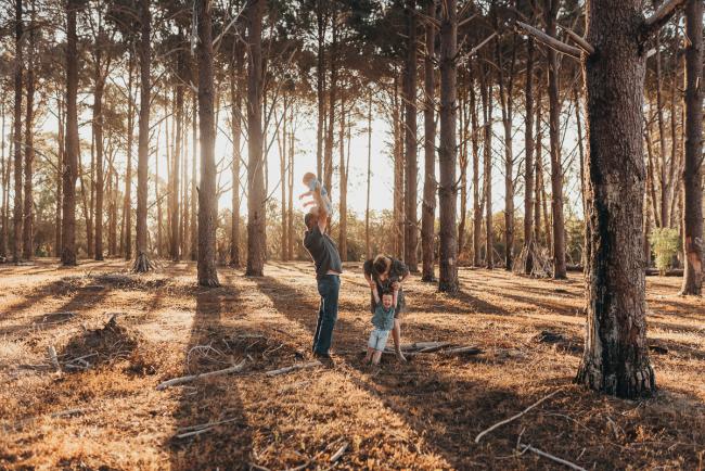 Father lifting son in the air and mother bending down to other son during Perth family photography session at The Pines Perth with Alana Prosper Photography