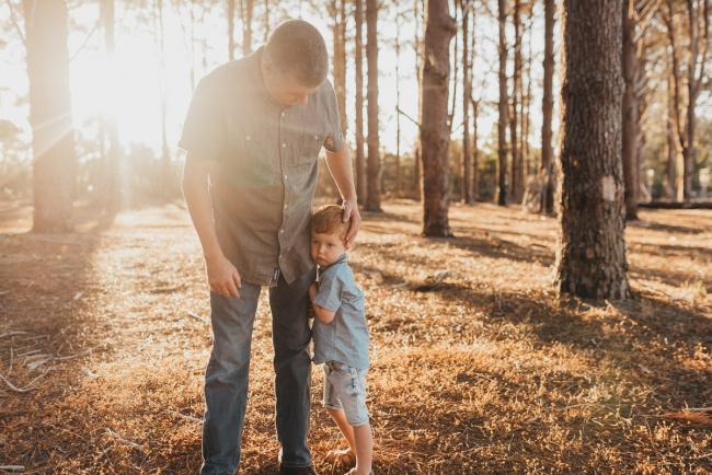 Little boy cuddling into fathers legs during Perth family photography session at The Pines Perth with Alana Prosper Photography