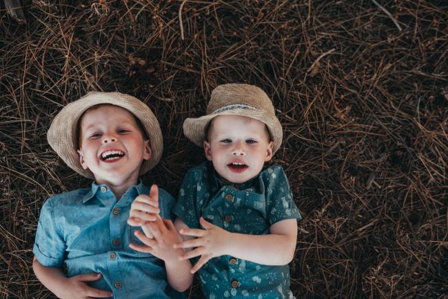 Two boys laying on the ground and laughing during Perth family photography session at The Pines Perth with Alana Prosper Photography