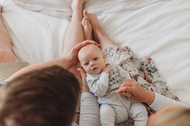 Perth-Newborn-Photographer-Alana-Prosper-Photography-21-of-31 baby laying on lap of parents with Perth lifestyle newborn photographer Alana Prosper Photography