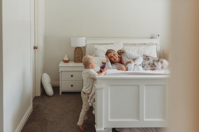 Perth-Newborn-Photographer-Alana-Prosper-Photography-24-of-31 mother laying on bed with baby, with son standing next to them playing with Perth lifestyle newborn photographer Alana Prosper Photography