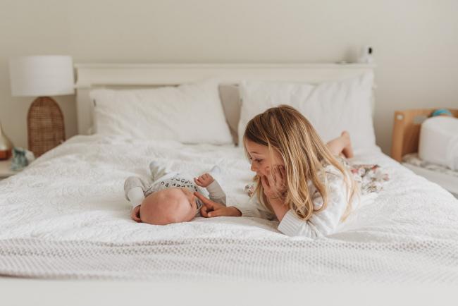 Perth-Newborn-Photographer-Alana-Prosper-Photography-28-of-31 sister laying on bed with baby with Perth lifestyle newborn photographer Alana Prosper Photography