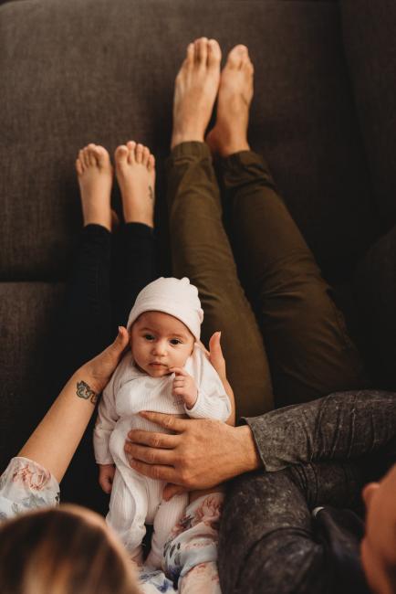 Top down image of baby on parents laps with Perth newborn lifestyle photographer