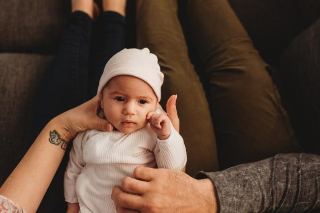 Newborn baby on parents laps with Perth newborn lifestyle photographer
