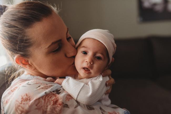 mother kissing newborn baby with Perth newborn lifestyle photographer