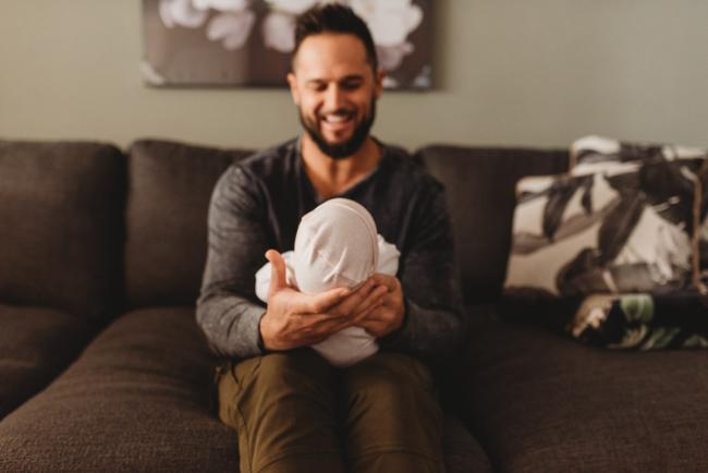 father holding newborn baby across legs with Perth newborn lifestyle photographer