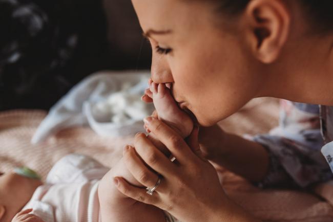 mother kissing baby foot with Perth newborn lifestyle photographer