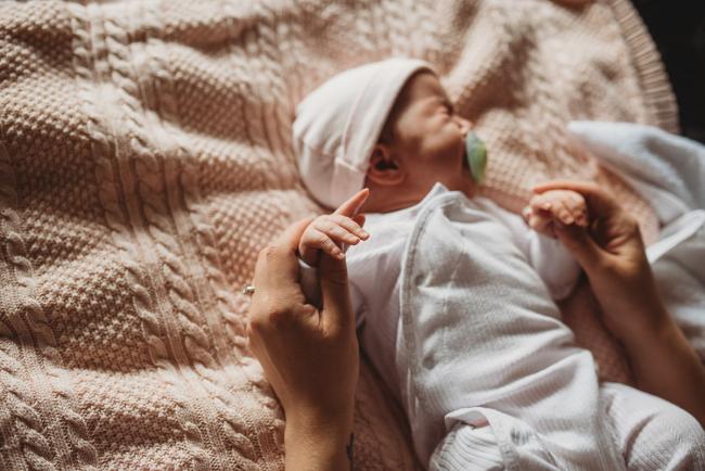 Mother holding baby's hands with Perth newborn lifestyle photographer