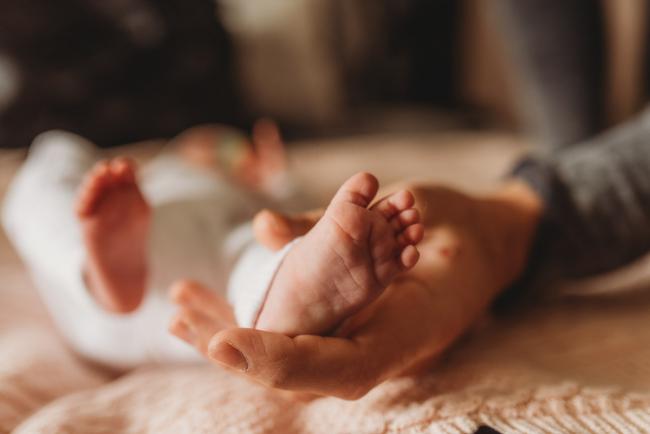 father holding baby foot with Perth newborn lifestyle photographer