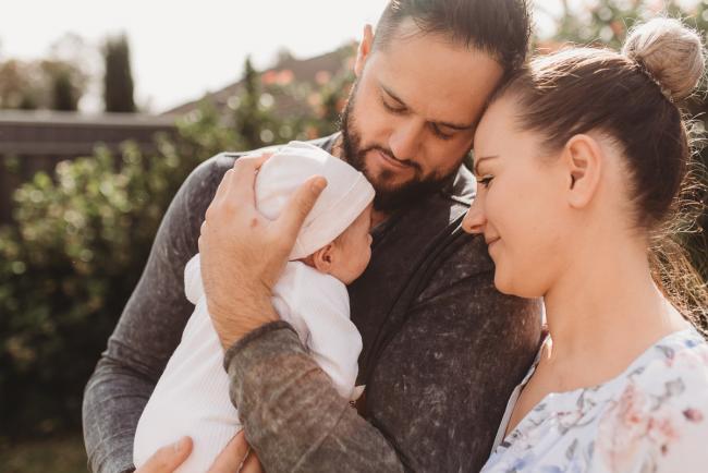 Parents holding newborn baby outside with Perth newborn lifestyle photographer