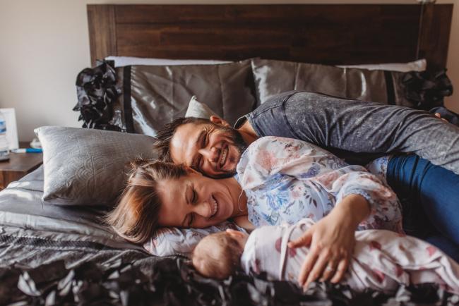 Parents laying on bed with baby with Perth newborn lifestyle photographer Alana Prosper Photography