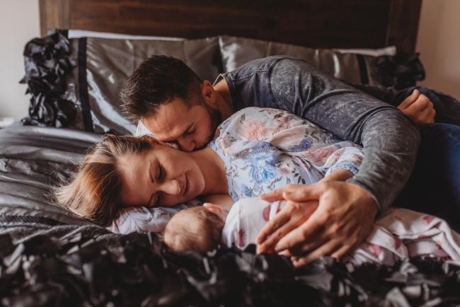 Parents laying on bed with baby with Perth newborn lifestyle photographer Alana Prosper Photography