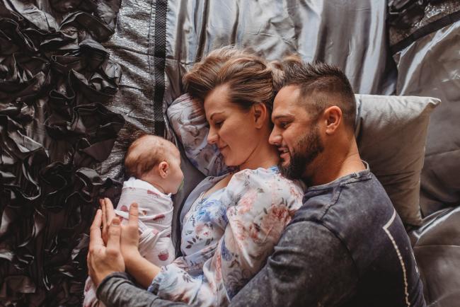 Parents laying on bed with baby with Perth newborn lifestyle photographer Alana Prosper Photography