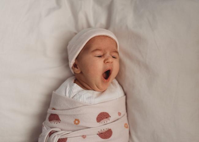 Newborn baby wrapped and yawning with Perth newborn lifestyle photographer