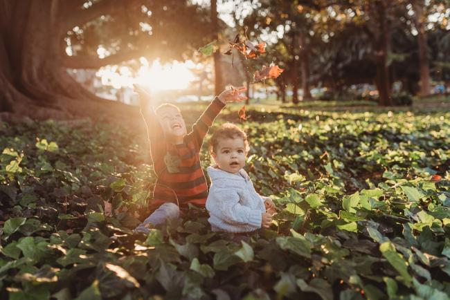 boy throwing leaves in grass with brother with Perth family photographer Alana Prosper Photography at Hyde Park