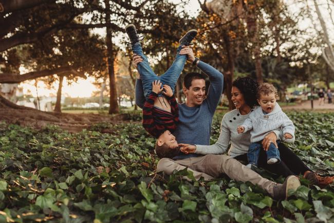 father lifting son upside down and mother with other son on her lap with Perth family photographer Alana Prosper Photography at Hyde Park
