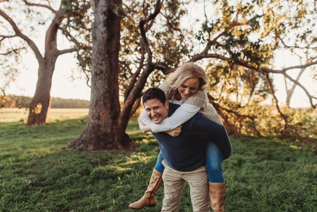 husband giving wife piggyback with Perth family photographer Alana Prosper Photography at Perry's Paddock