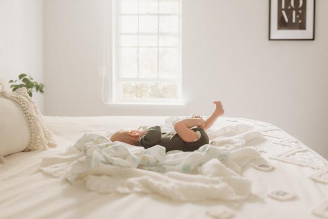 baby laying on bed by window with Perth Newborn Photographer