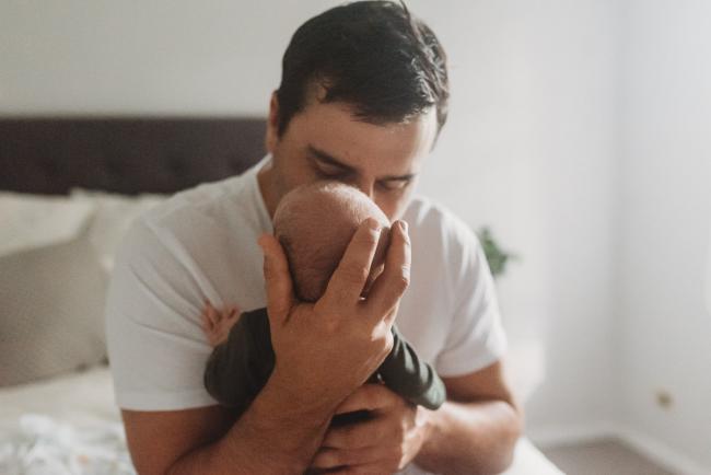 father holding baby head in his hands and kissing him with Perth Newborn photographer
