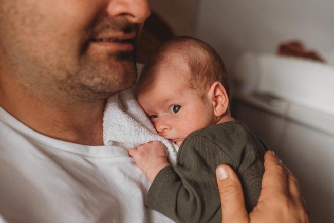 baby snuggles into father's chest with Perth Newborn photographer